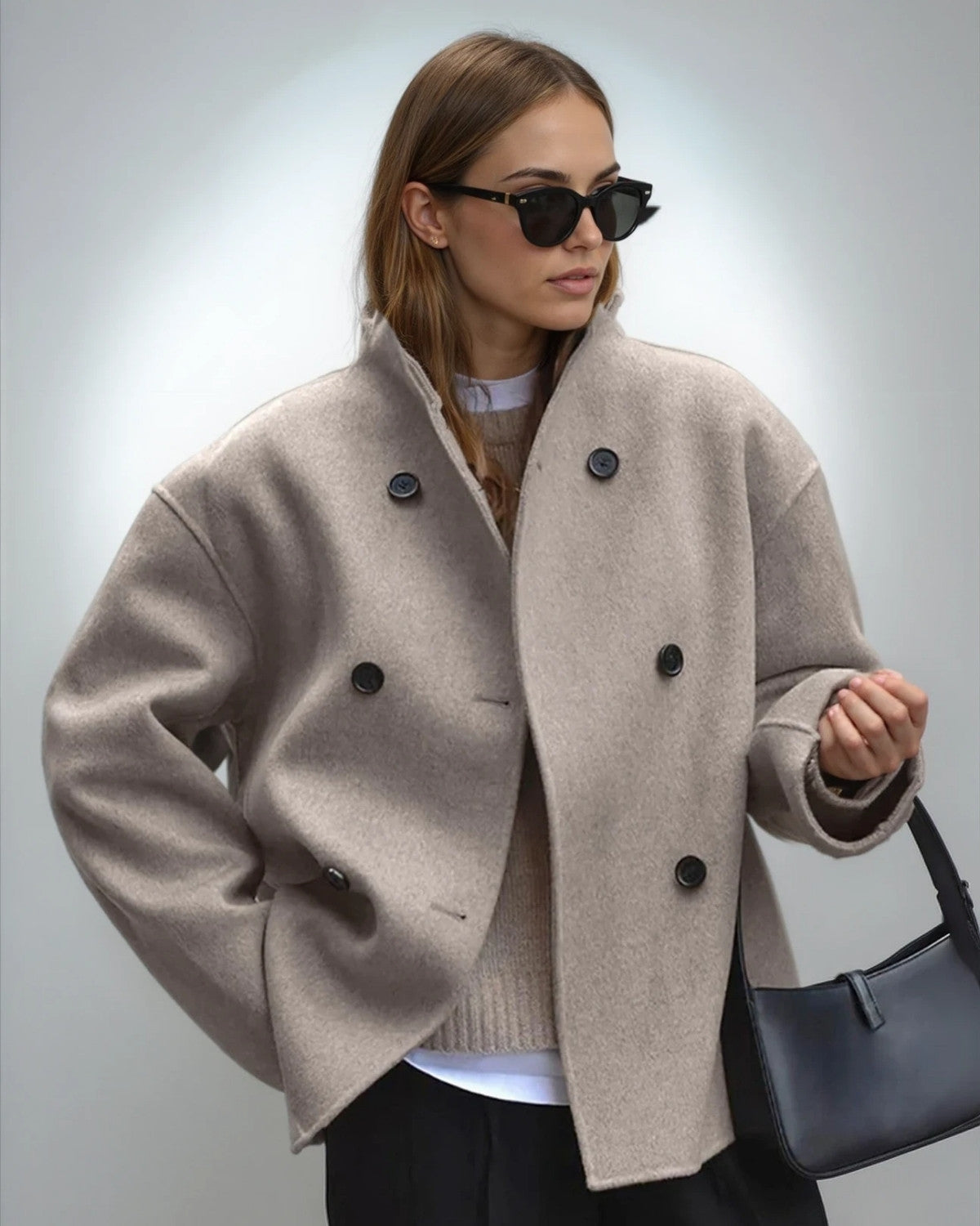 Frau mit beiger Wolljacke, schwarzer Sonnenbrille und schwarzer Handtasche. Modetrend Herbst, stilvolle Damenbekleidung, elegante Accessoires.