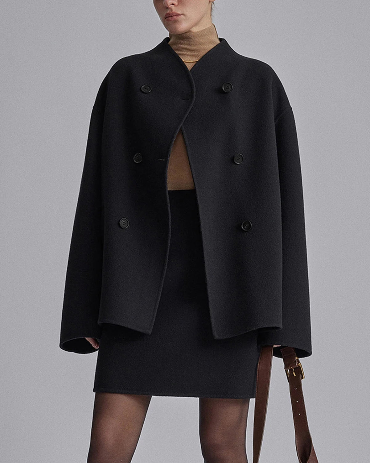 Damenmode: Eleganter schwarzer Wollmantel mit doppelter Knopfleiste, kombiniert mit Rock und Rollkragenpullover. Herbst-Winter-Outfit.