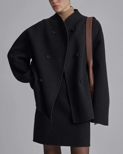 Damenmode: Eleganter schwarzer Wollmantel mit doppelter Knopfleiste, kombiniert mit brauner Umhängetasche. Herbst-Winter-Trend 2023.