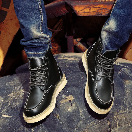 Schwarze Lederstiefel mit heller Sohle auf Jeans, getragen auf einem großen Reifen. Modische Herrenstiefel, robustes Design, Outdoor-Look.