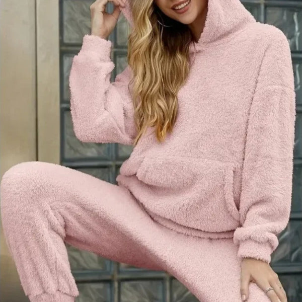 Frau in rosa Fleece-Hoodie und Jogginghose, lässige Mode, gemütlicher Look, Herbst-Winter-Outfit, bequeme Damenbekleidung, urbaner Stil.