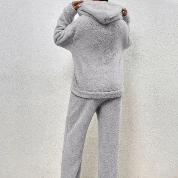 Person in grauem Fleece-Hoodie und Jogginghose, Rückansicht. Bequeme, warme Freizeitkleidung, ideal für kalte Tage. Kuscheliger Stoff, modisch und gemütlich.