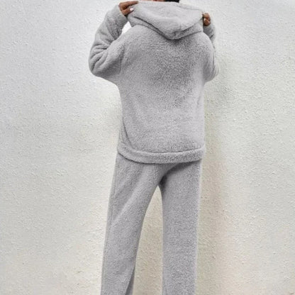 Person in grauem Fleece-Hoodie und Jogginghose, Rückansicht. Bequeme, warme Freizeitkleidung, ideal für kalte Tage. Kuscheliger Stoff, modisch und gemütlich.