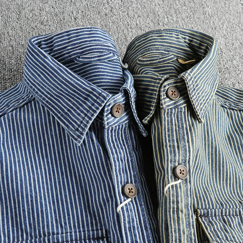 Zwei gestreifte Hemden aus Denim-Stoff, blau und grün, mit Holzknöpfen auf grauem Hintergrund. Modische Herrenbekleidung, lässiger Stil.