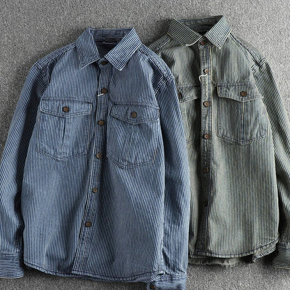 Zwei gestreifte Hemden aus Baumwolle, blau und grün, mit Brusttaschen und Knöpfen, auf grauem Hintergrund. Herrenmode, Freizeitkleidung.