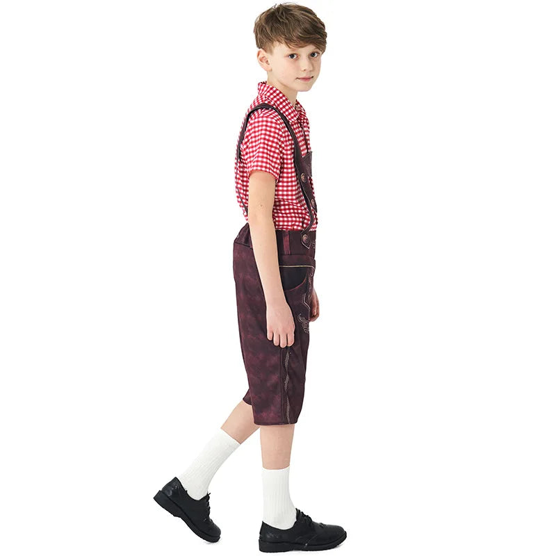 Junge in traditioneller bayerischer Tracht mit rotem Karohemd und brauner Lederhose, seitlich stehend. Oktoberfest Kinderkleidung.