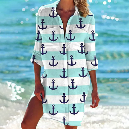 Frau am Strand in einem maritimen Strandkleid mit Anker-Muster, türkis-weiß gestreift. Sommermode, Strandoutfit, maritimer Stil.