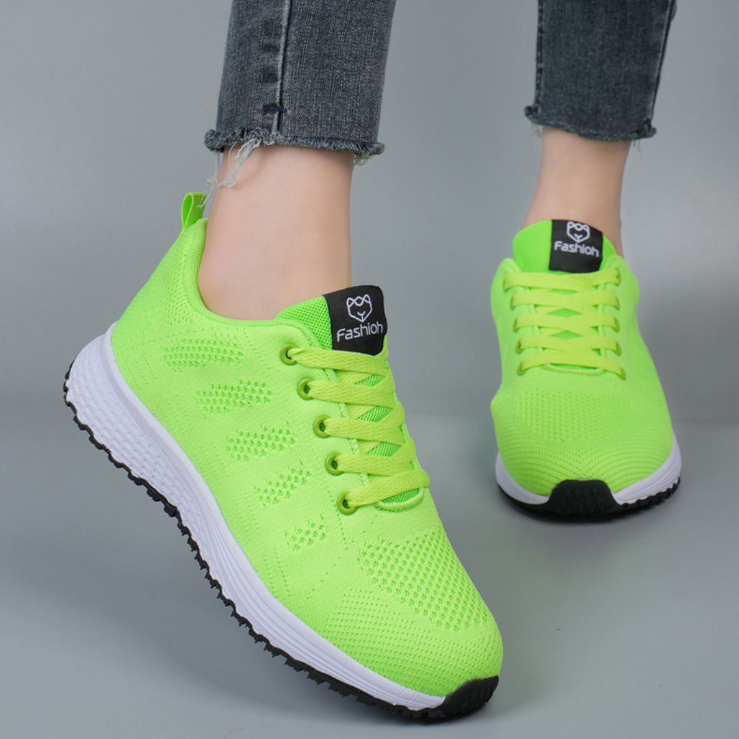 Neon-grüne Sportschuhe mit weißer Sohle, getragen von Person in Jeans. Modische, atmungsaktive Sneaker für Damen, ideal für Freizeit und Sport.