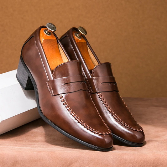 Braune Herren-Lederloafer mit Absatz auf beigem Hintergrund. Elegante, handgefertigte Schuhe, ideal für formelle Anlässe und Business-Outfits.