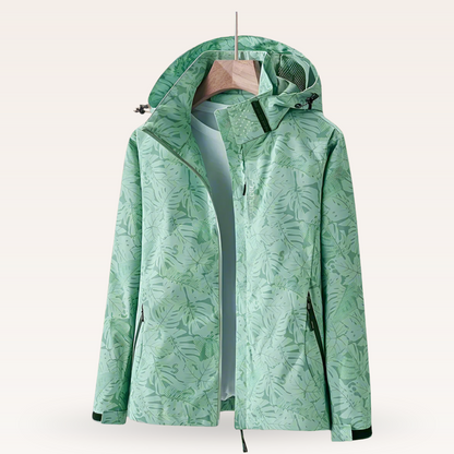 Grüne Damen-Regenjacke mit tropischem Blattmuster, Kapuze und Reißverschluss, ideal für Outdoor-Aktivitäten und modische Freizeitkleidung.