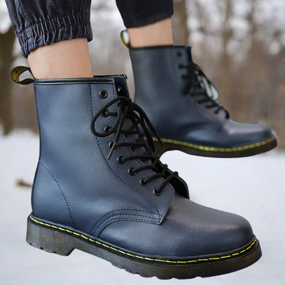 Schwarze Lederstiefel mit gelber Naht, geschnürt, auf schneebedecktem Boden. Modische Winterstiefel, robust und stilvoll für kalte Tage.