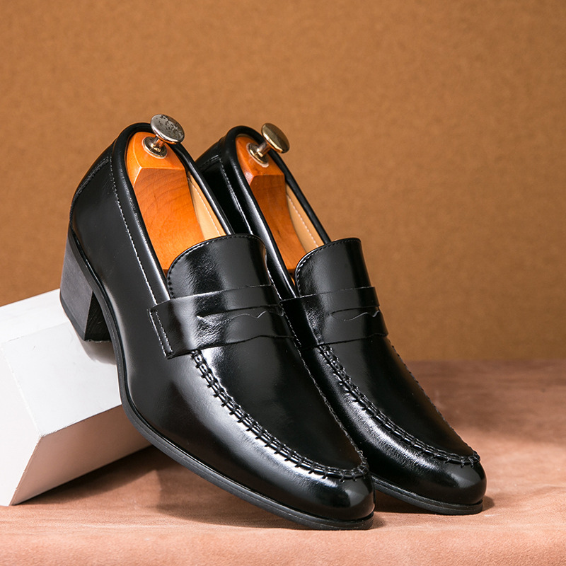 Schwarze Herren-Lederslipper mit Absatz, elegant und glänzend, auf braunem Hintergrund. Perfekt für formelle Anlässe und Business-Outfits.
