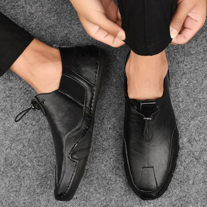 Schwarze Herren-Lederslipper, elegant und modern, auf grauem Teppich. Bequeme Freizeitschuhe, ideal für Büro oder Alltag.