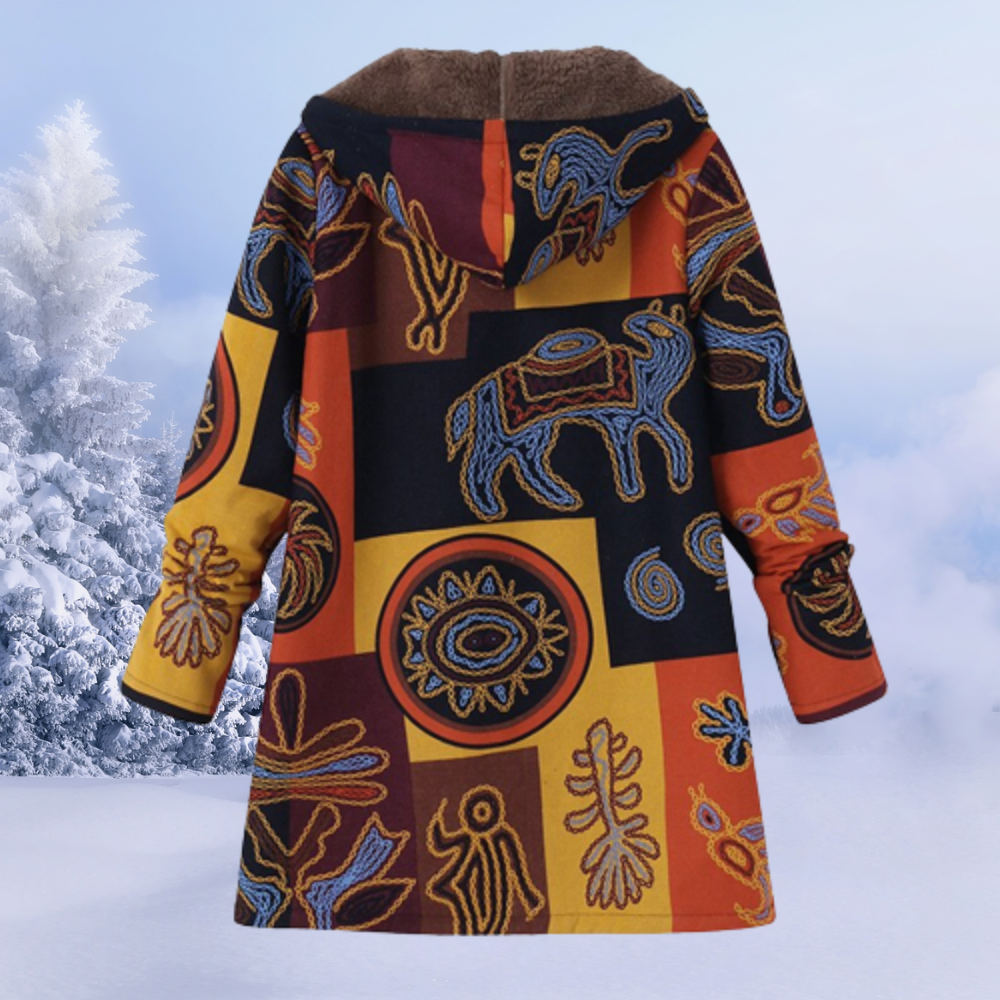 Bunter Wintermantel mit ethnischen Mustern, Kapuze und warmem Futter vor schneebedeckter Landschaft. Ideal für kalte Wintertage.