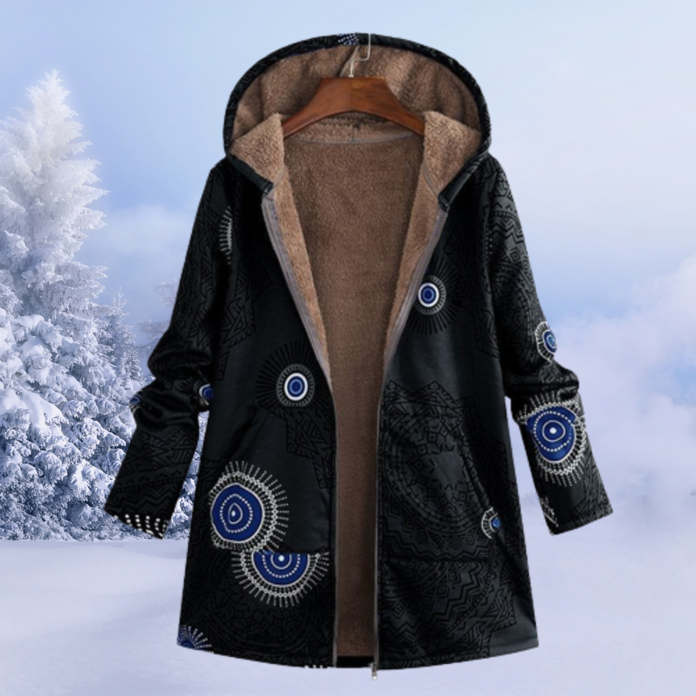Schwarzer Wintermantel mit Kapuze, blau-weißen Mandala-Mustern und warmem Futter, vor schneebedeckter Landschaft. Ideal für kalte Wintertage.