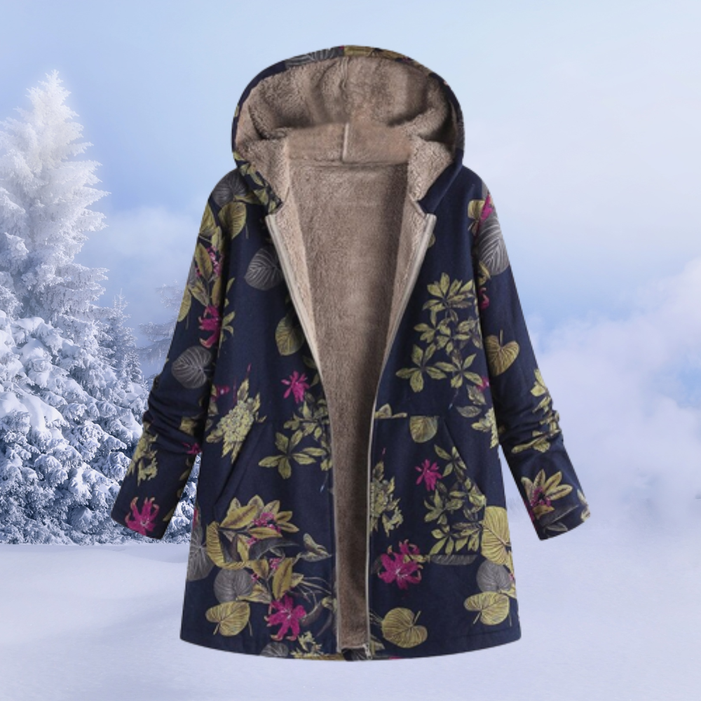 Damen Wintermantel mit Kapuze, florales Muster, warmes Futter, blau, vor verschneiter Landschaft. Ideal für kalte Wintertage.