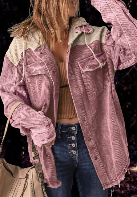Frau in rosa Cordjacke mit Kapuze, braunem Top und blauer Jeans. Modetrend Herbst, lässiger Streetstyle, Damenmode.