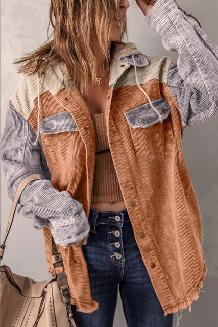 Frau in modischer Cordjacke mit Farbblock-Design, kombiniert mit Jeans und beiger Handtasche. Trendige Herbstmode, lässiger Streetstyle.