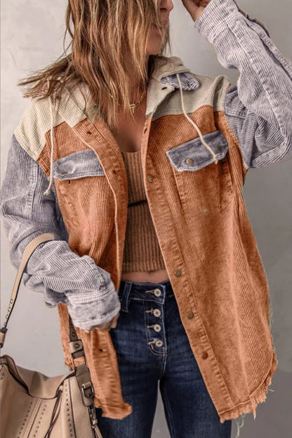 Frau in modischer Cordjacke mit Farbblock-Design, kombiniert mit Jeans und beiger Handtasche. Trendige Herbstmode, lässiger Streetstyle.