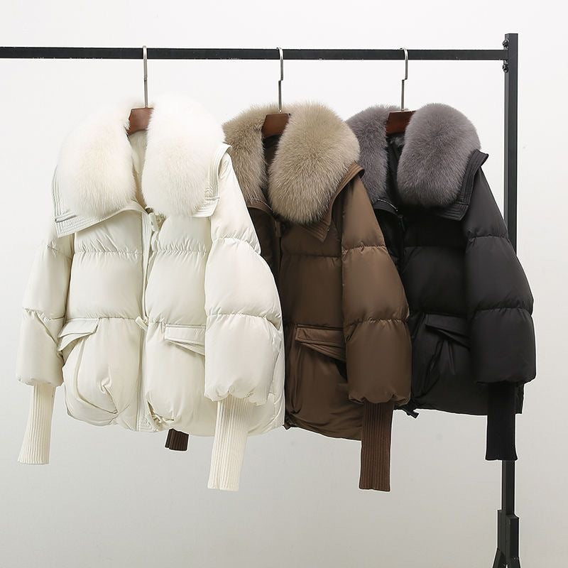 Drei Daunenjacken mit Pelzkragen in Weiß, Braun und Schwarz auf Kleiderstange. Wintermode, warme Jacken, stilvolle Oberbekleidung.