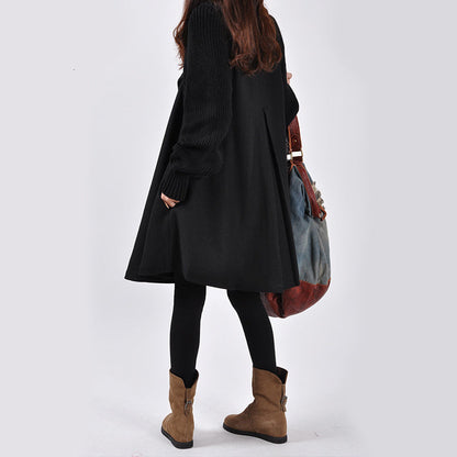 Frau in schwarzem Mantel und Stiefeln, trägt eine große, bunte Tasche. Mode, Winterkleidung, Damenoutfit, stilvoll, lässig.