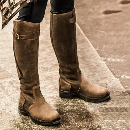 Braune Lederstiefel, kniehoch, mit Schnallen, auf nassem Asphalt. Modische Damenstiefel, ideal für Herbstmode und Outdoor-Aktivitäten.