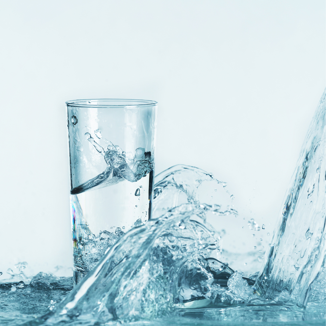 Ein Glas Wasser mit spritzendem Wasser, das über den Rand fließt. Frisches, klares Trinkwasser, Hydration, Erfrischung, gesunde Lebensweise.