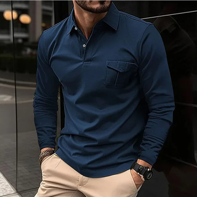 Mann in dunkelblauem Langarm-Poloshirt und beigen Hosen, steht vor einem modernen Gebäude. Stilvolle Herrenmode, urbaner Look.