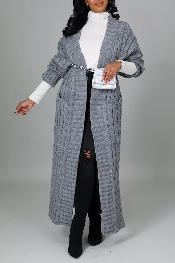 Frau in grauem Strickmantel mit Gürtel, weißem Rollkragenpullover, schwarzer Hose und Stiefeln. Elegante Wintermode, stilvoller Look.