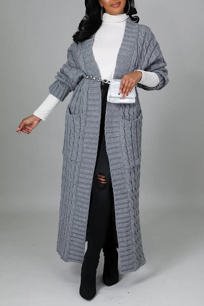 Frau in grauem Strickmantel mit Gürtel, weißem Rollkragenpullover, schwarzer Hose und Stiefeln. Elegante Wintermode, stilvoller Look.