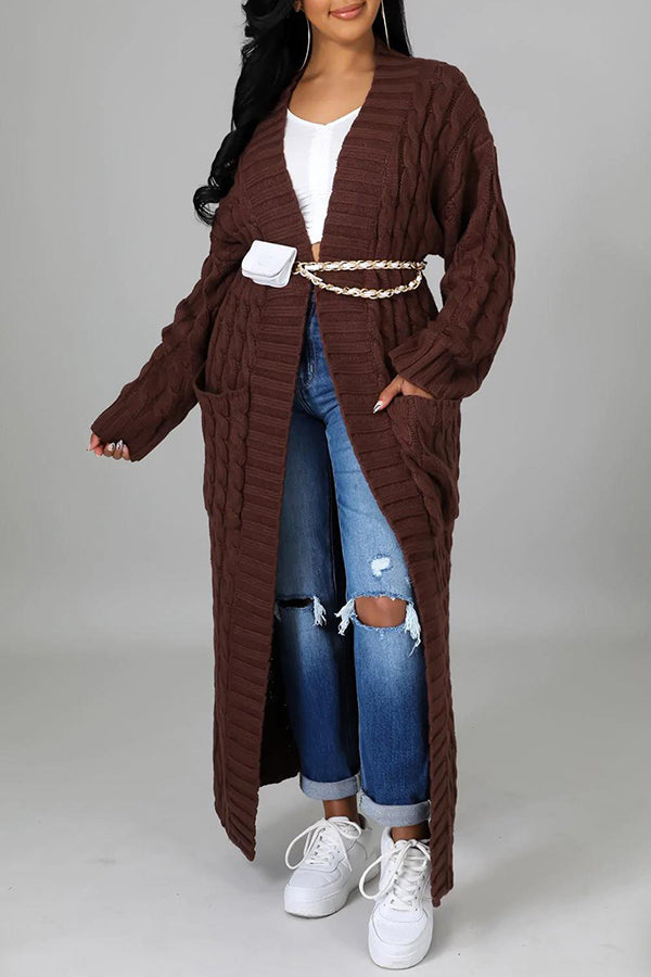 Frau in braunem Strick-Cardigan mit Gürtel, zerrissenen Jeans und weißen Sneakers. Modetrend, Herbstmode, lässiger Look.