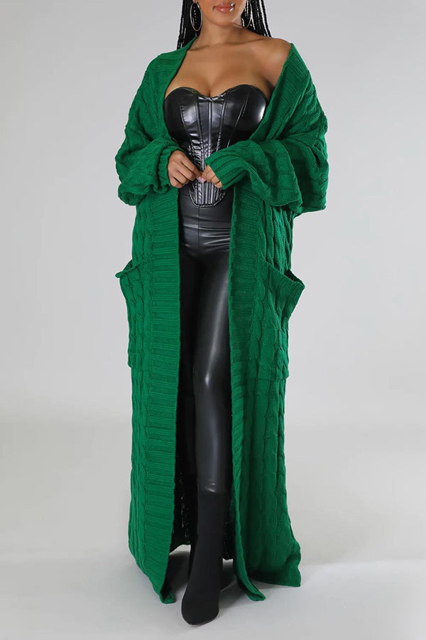Frau in schwarzem Leder-Outfit mit langem, grünem Strickmantel, Taschen, modisch, elegant, Herbstmode, Damenbekleidung, trendiger Look.