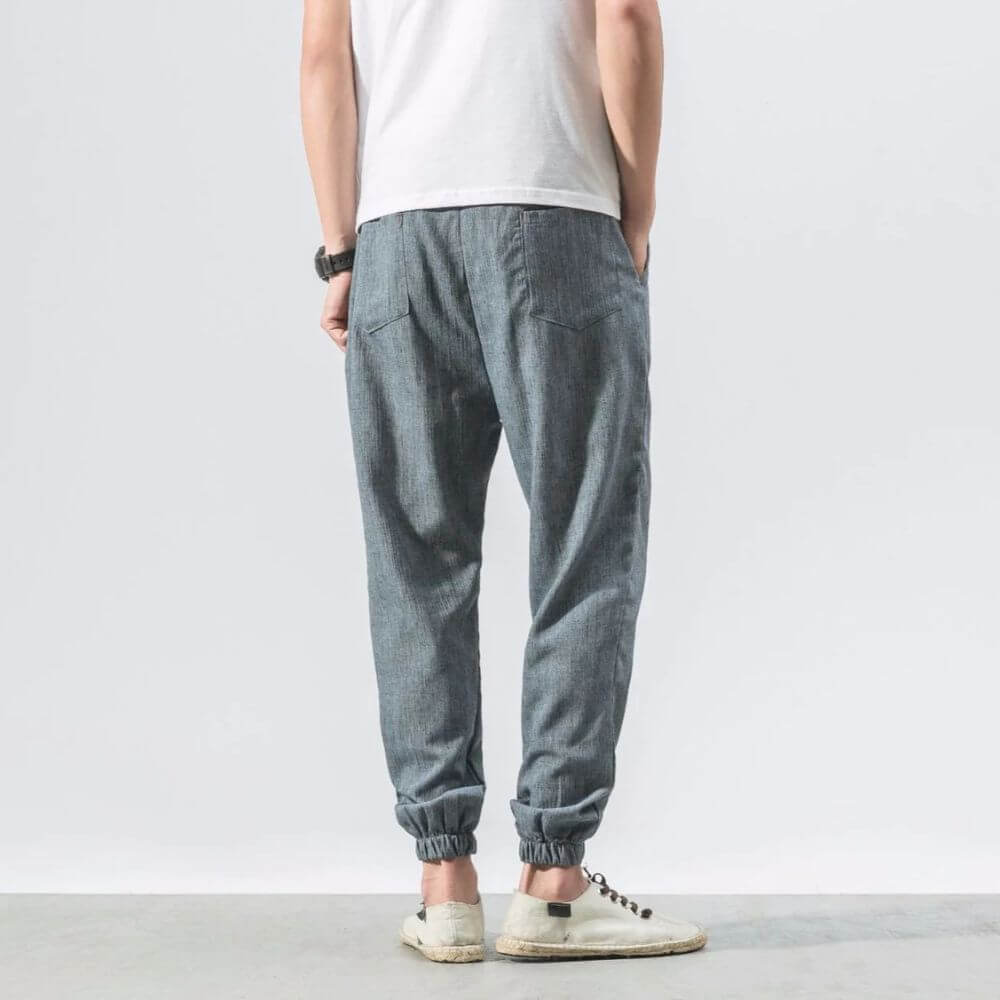 Person in grauer Jogginghose und weißem T-Shirt, Rückansicht. Lässige Mode, bequeme Freizeitkleidung, moderne Herrenbekleidung.