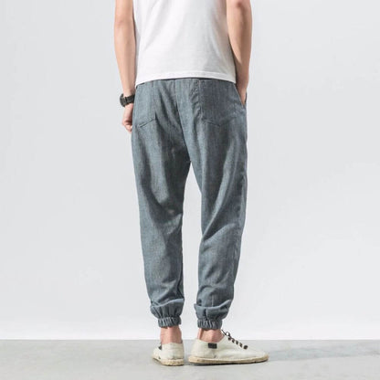 Person in grauer Jogginghose und weißem T-Shirt, Rückansicht. Lässige Mode, bequeme Freizeitkleidung, moderne Herrenbekleidung.