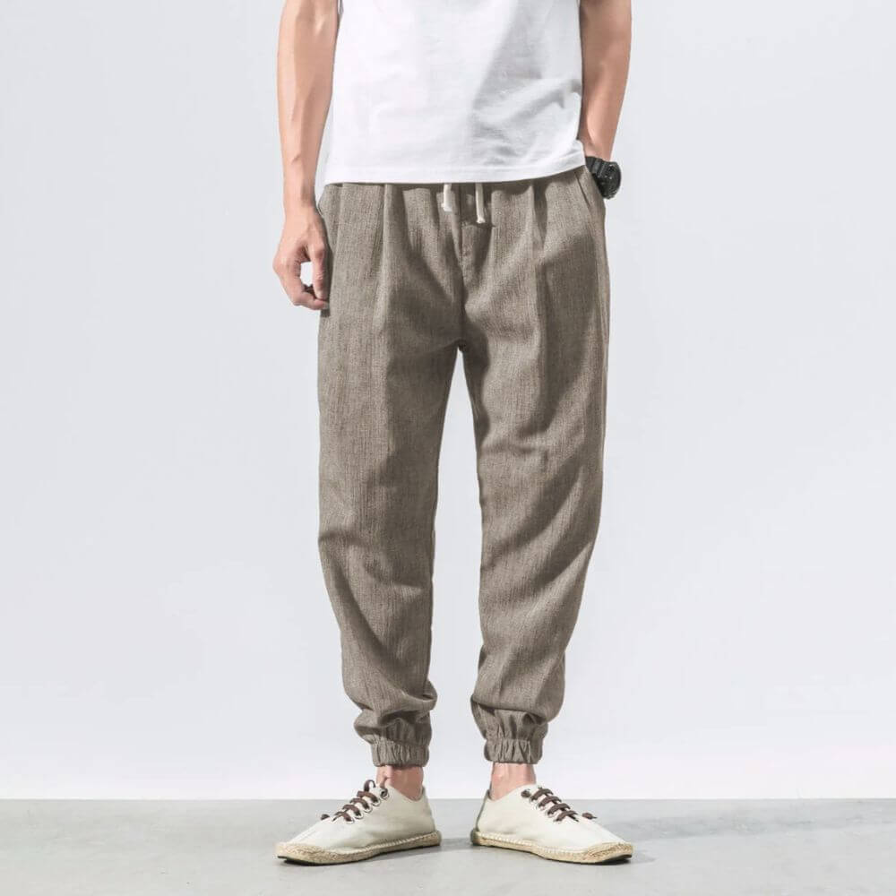 Herren Leinen Jogginghose in Beige, lässiger Stil, kombiniert mit weißem T-Shirt und Sneakers. Bequeme Freizeitmode für Männer.