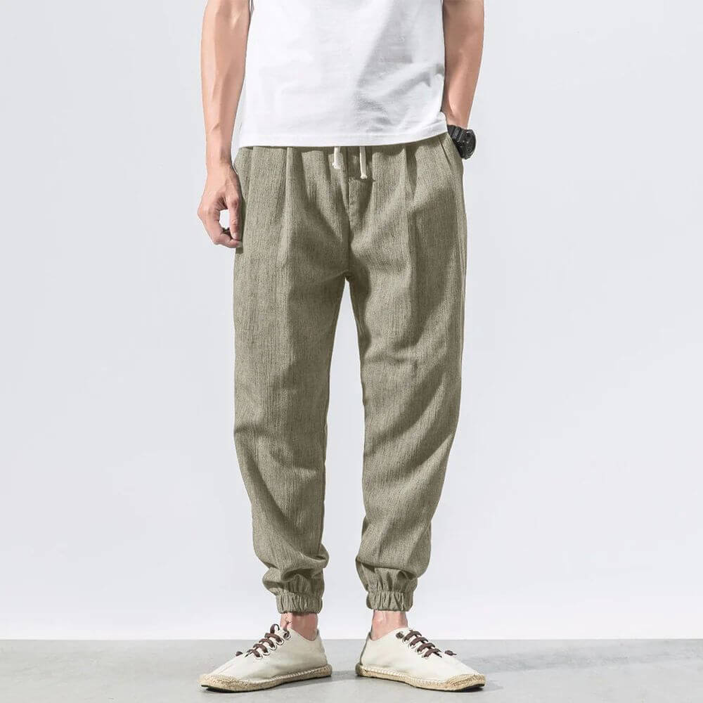 Herren Leinenhose in Beige, lässiger Stil, elastischer Bund, ideal für Sommermode. Kombiniert mit weißem T-Shirt und Freizeitschuhen.