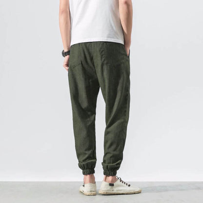 Rückansicht einer Person in olivgrüner Jogginghose und weißem T-Shirt, lässiger Stil, bequeme Freizeitkleidung, modische Herrenmode.