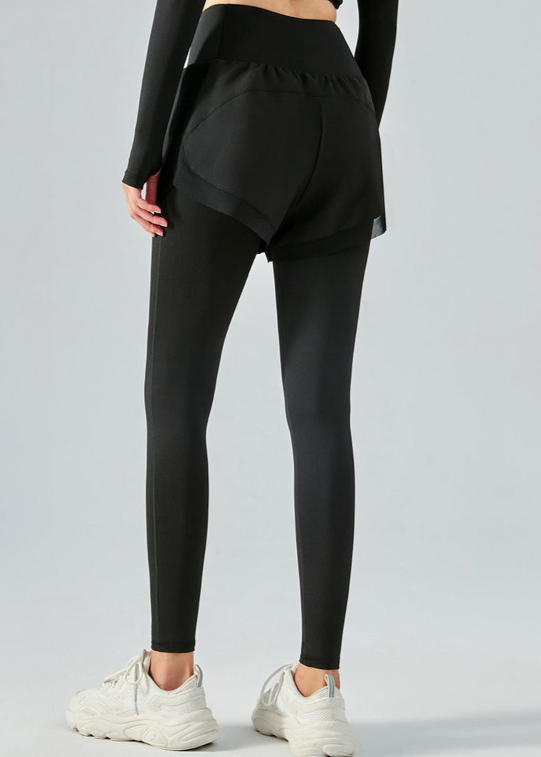 Frau in schwarzer Sportleggings mit Shorts, Rückansicht. Trägt weiße Turnschuhe. Fitnessmode, Sportbekleidung, bequeme Trainingskleidung.