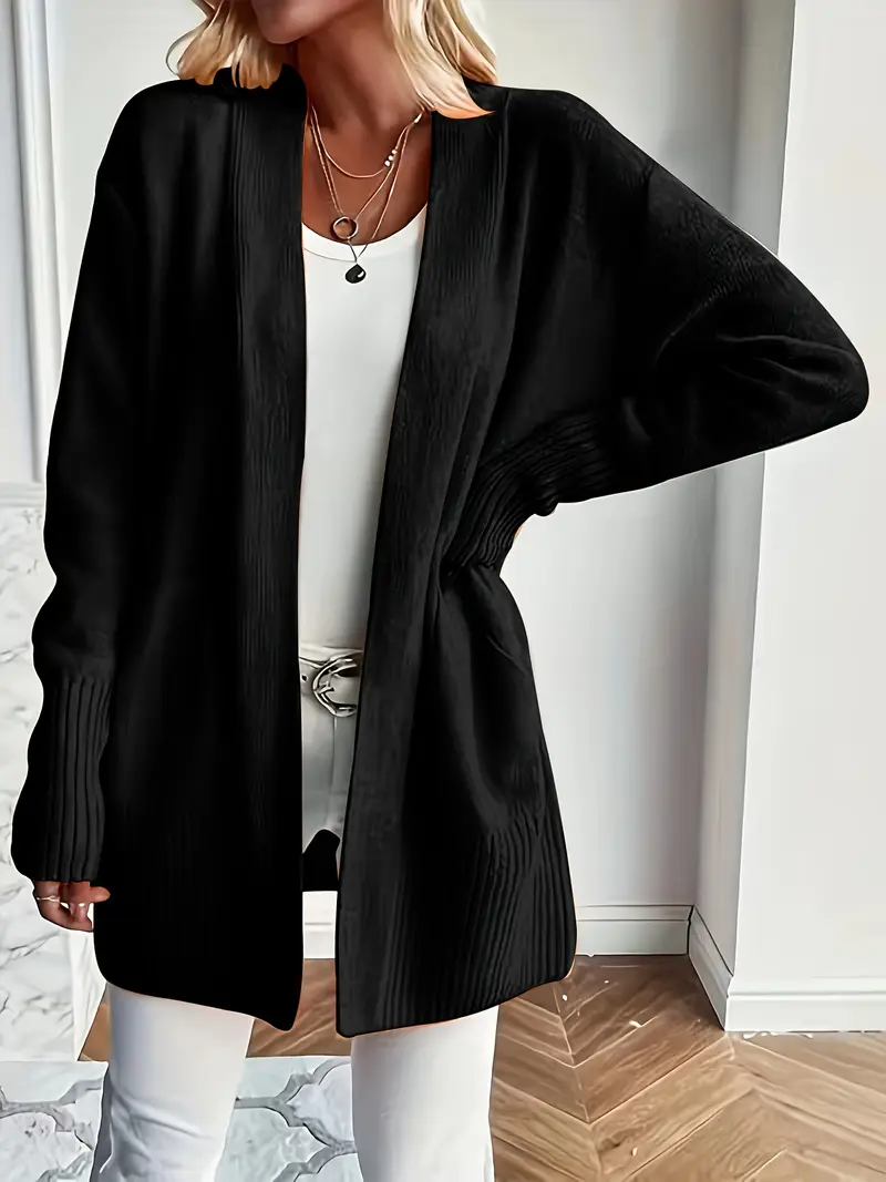 Schwarzer Damen-Cardigan, offen getragen, kombiniert mit weißem Top und Hose. Modischer Look, ideal für Herbstmode und elegante Outfits.