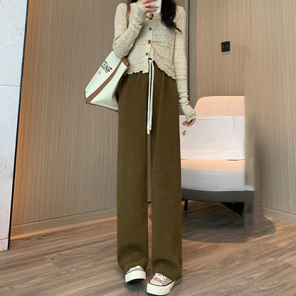 Frau in modischer Herbstkleidung: Beige Strickjacke, braune weite Hose, weiße Sneakers. Trendiger Look, ideal für kühle Tage.