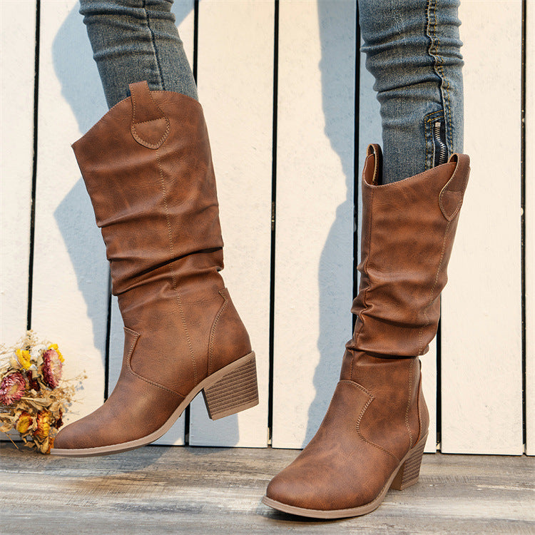 Braune Cowboystiefel aus Leder mit Blockabsatz, getragen von Person in Jeans. Modische Damenstiefel, ideal für Herbstmode und Western-Look.