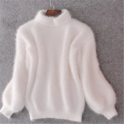 Weiße flauschige Damenpullover aus Angorawolle mit langen Ärmeln und Rollkragen, hängend an einem Holzbügel vor grauem Hintergrund.