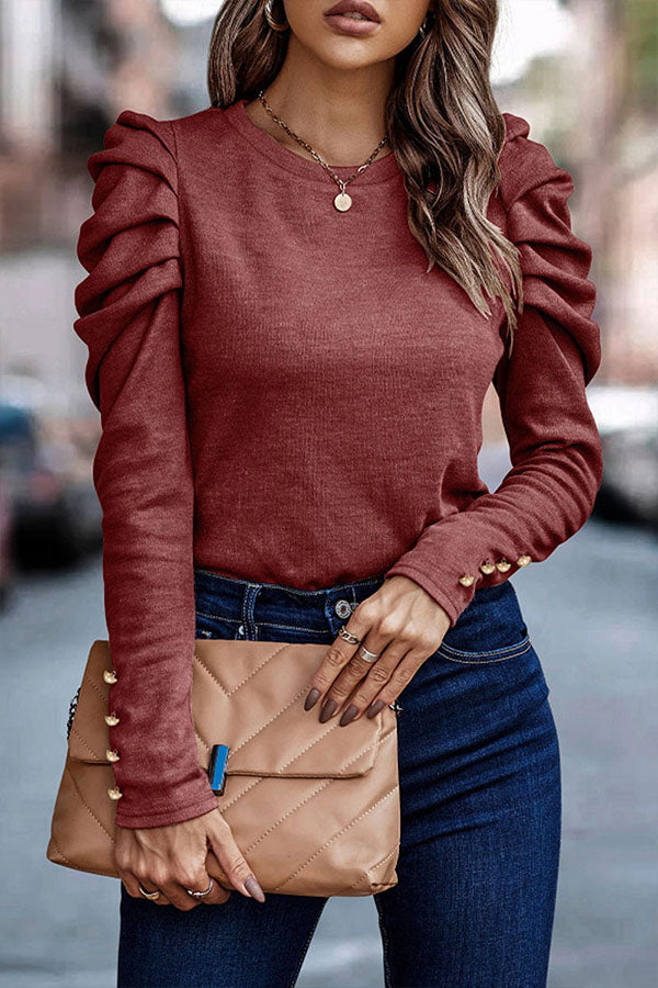 Frau in rotem Rüschenpullover und blauer Jeans hält beige gesteppte Clutch. Modetrend, Damenmode, stilvolles Outfit, Herbstmode.
