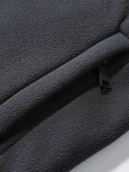 Dunkelgraue Fleecejacke mit Reißverschluss, Nahaufnahme. Weiches, warmes Material, ideal für Outdoor-Aktivitäten und kaltes Wetter.