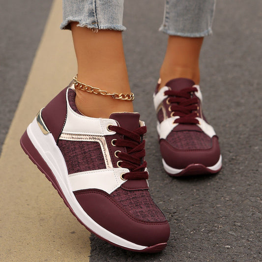 Damen Sneaker in Bordeaux und Weiß auf Asphalt, goldene Fußkette, modische Sportschuhe, Freizeitlook, Jeans, Straßenhintergrund.