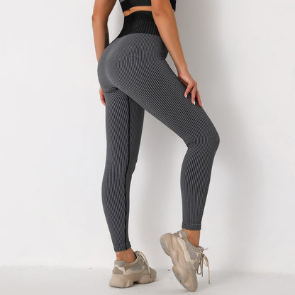 Frau in grauer, gerippter Leggings und beigen Sneakers vor weißem Hintergrund. Sportmode, Fitnessbekleidung, bequeme Leggings.