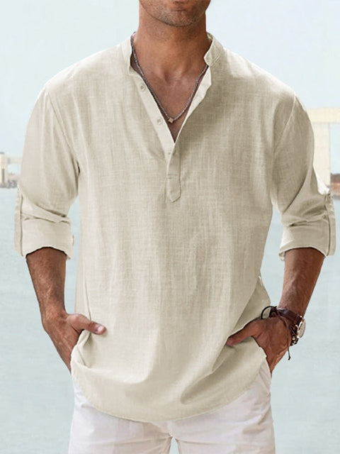 Mann in beigem Leinenhemd mit Stehkragen und hochgekrempelten Ärmeln, lässiger Sommerlook, modisch und bequem, ideal für Strand oder Freizeit.