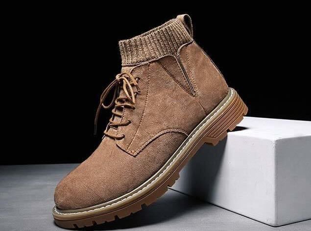 Brauner Wildlederstiefel mit Schnürung und gerippter Knöchelmanschette auf weißem Podest, modisch, robust, ideal für Herbst- und Wintermode.