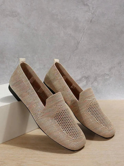Beige gestrickte Loafer-Schuhe auf Holz- und Betonhintergrund, stilvoll und modern, ideal für Freizeitmode und Komfort.