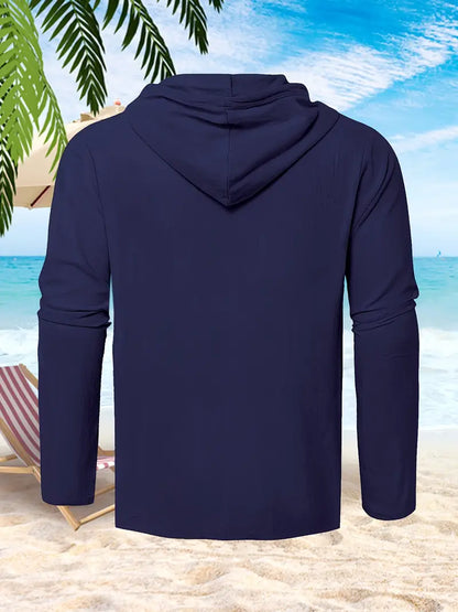 Dunkelblauer Kapuzenpullover am Strand, Palmen und Liegestuhl im Hintergrund, ideal für Sommermode und Freizeitkleidung.